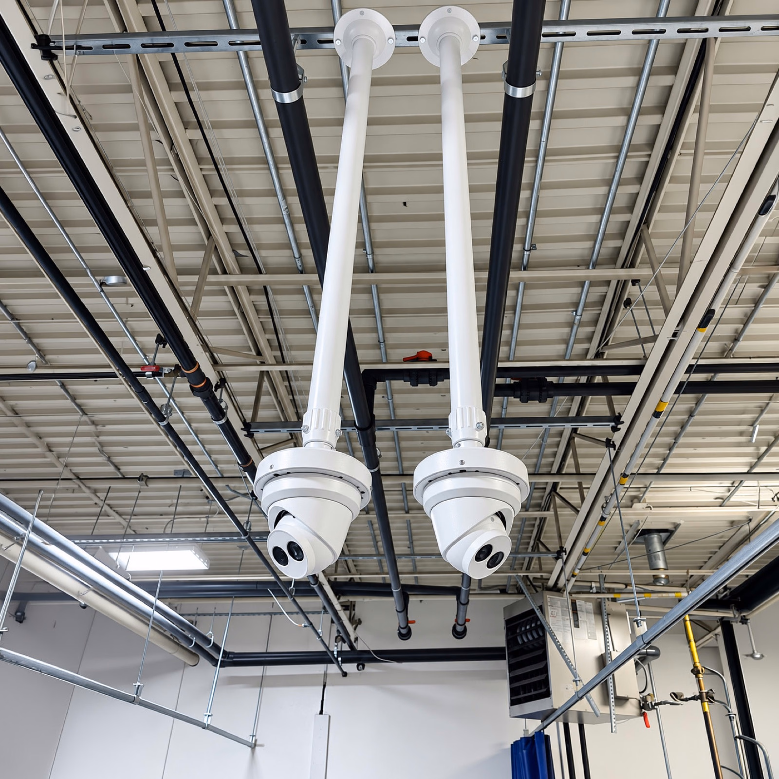 Two security cameras mounted on ceiling poles at an Etobicoke commercial property