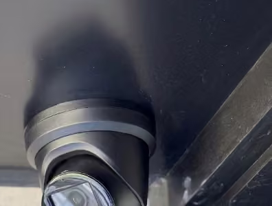 Dome security camera mounted beneath a dark exterior overhang.