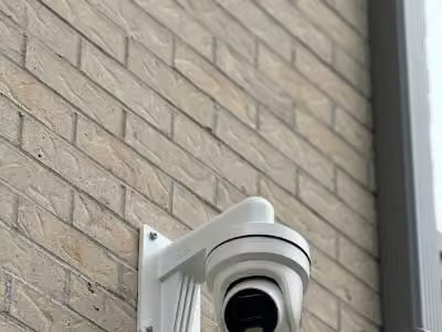 White dome security camera on a brick wall.