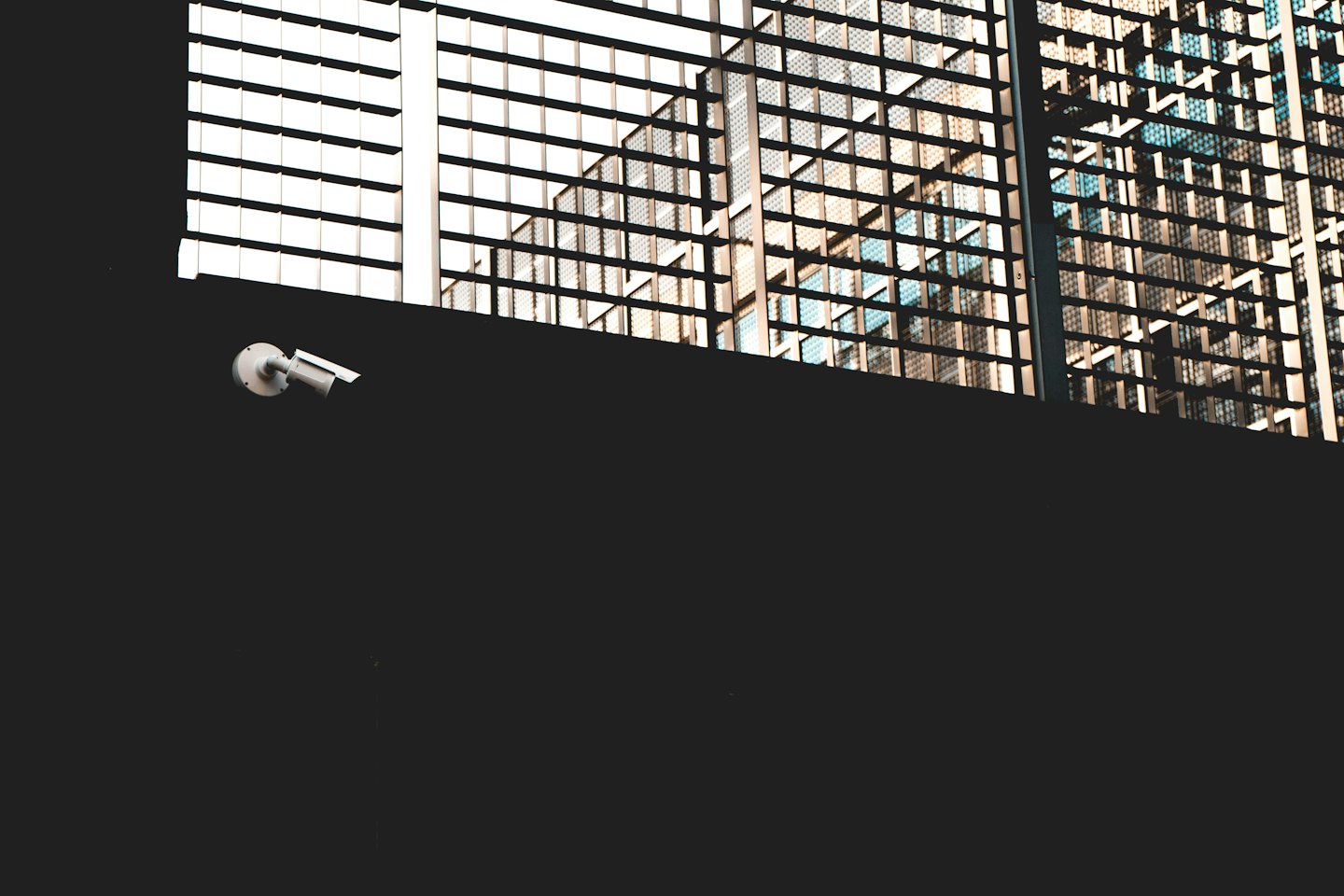 Security camera mounted on a wall overlooking a modern building.