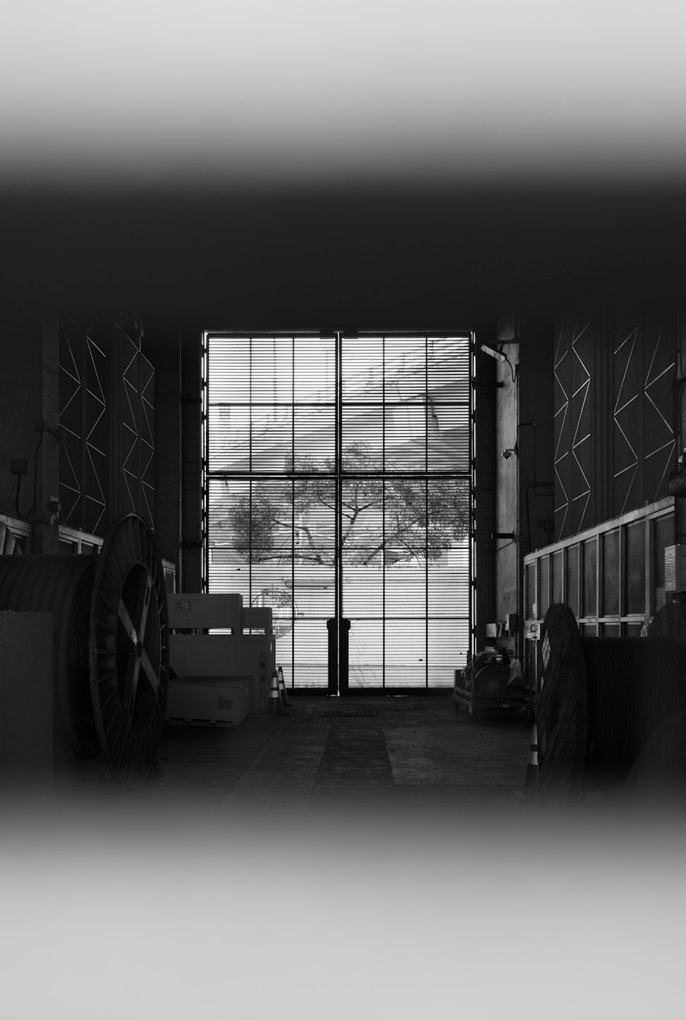 Cable spools in a dark industrial warehouse looking through barred windows.