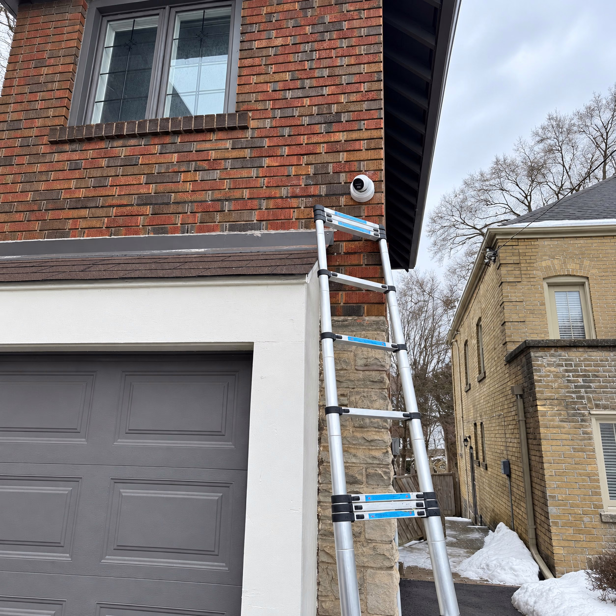 Security camera installed on a brick house beside an installation ladder