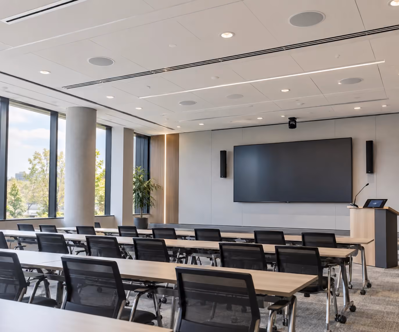 Commercial training room with ceiling speakers, a large display, and presentation equipment