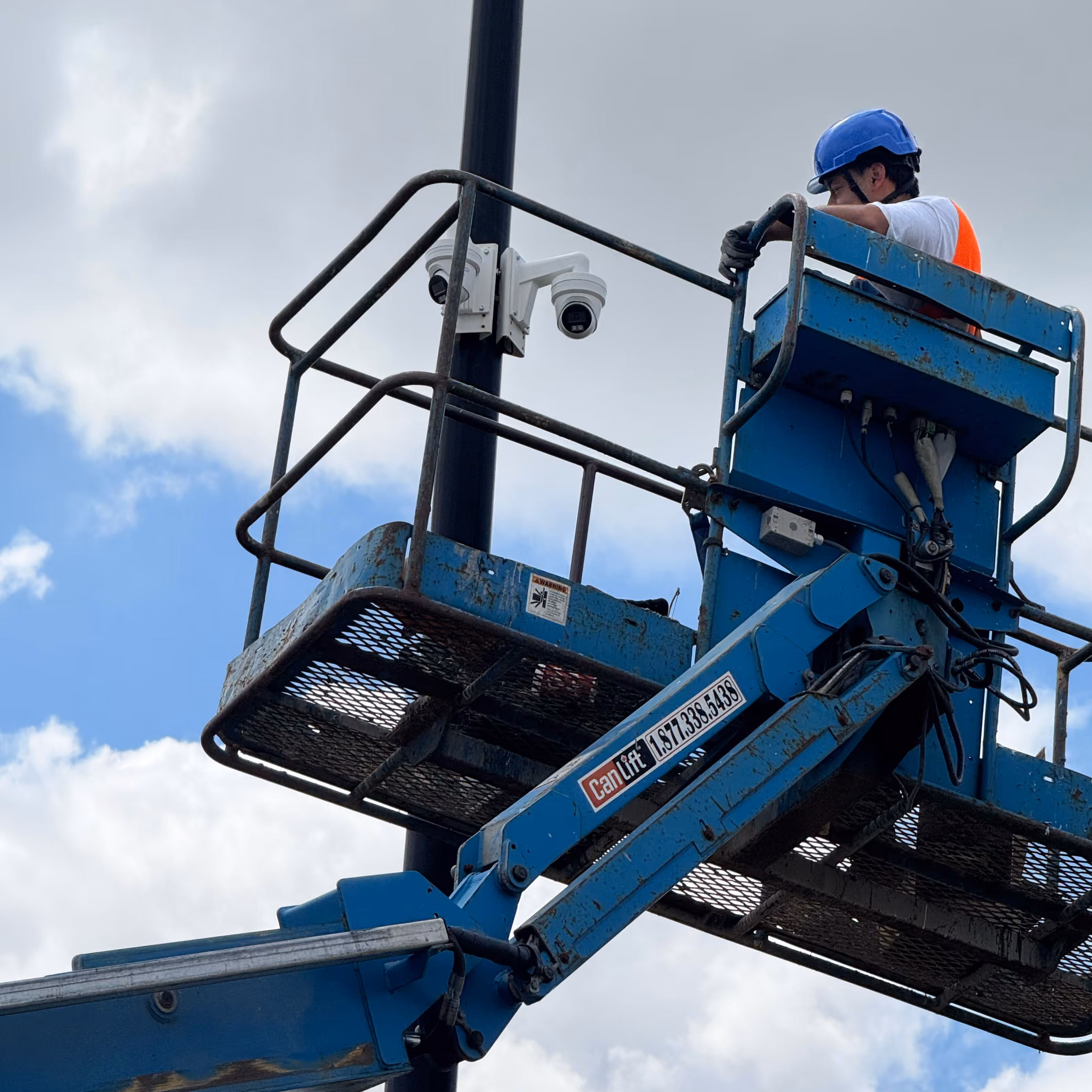 Technician installing commercial security cameras from a lift