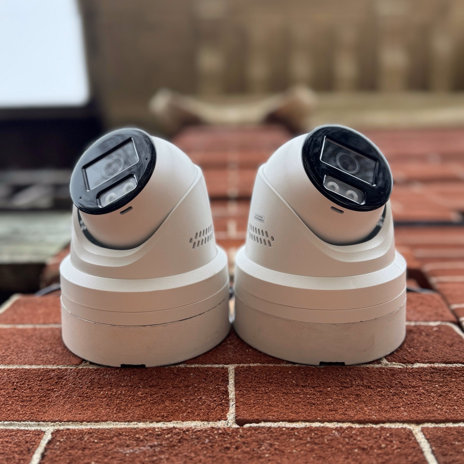 Two white security cameras resting on a brick ledge in Newmarket