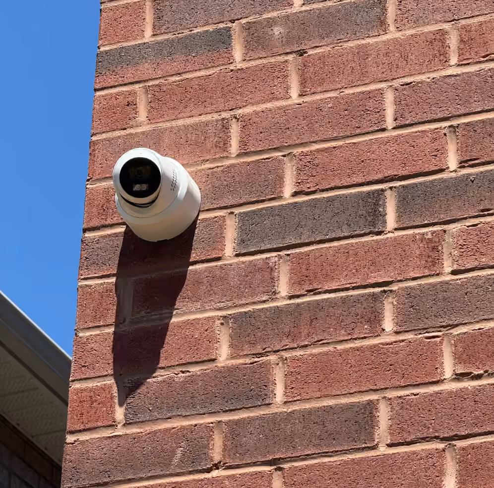 White outdoor security camera mounted on a red brick wall in Toronto and the GTA