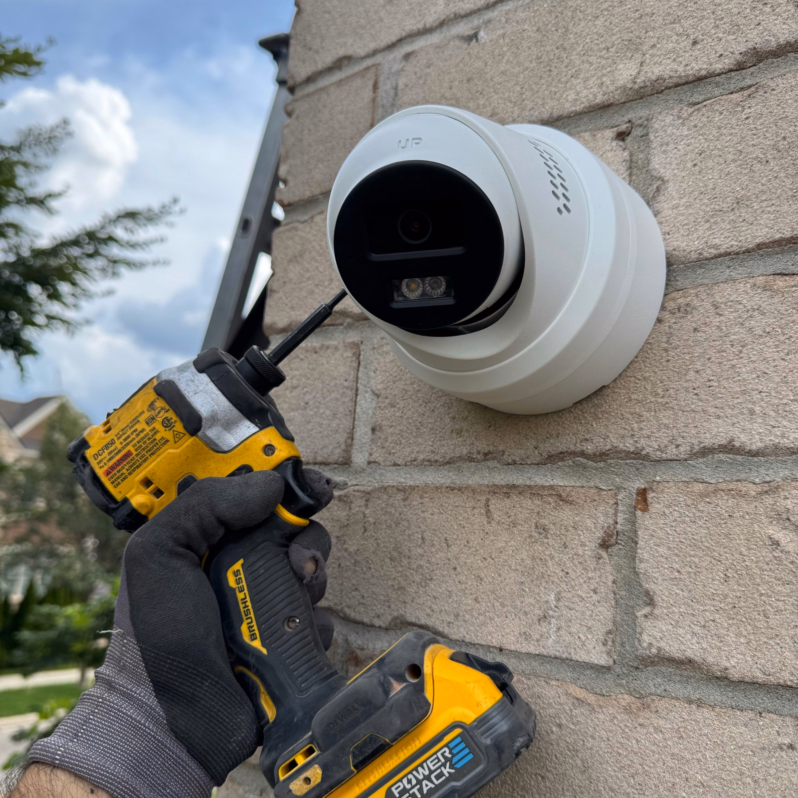 Technician using a drill beside a wall-mounted security camera in Richmond Hill