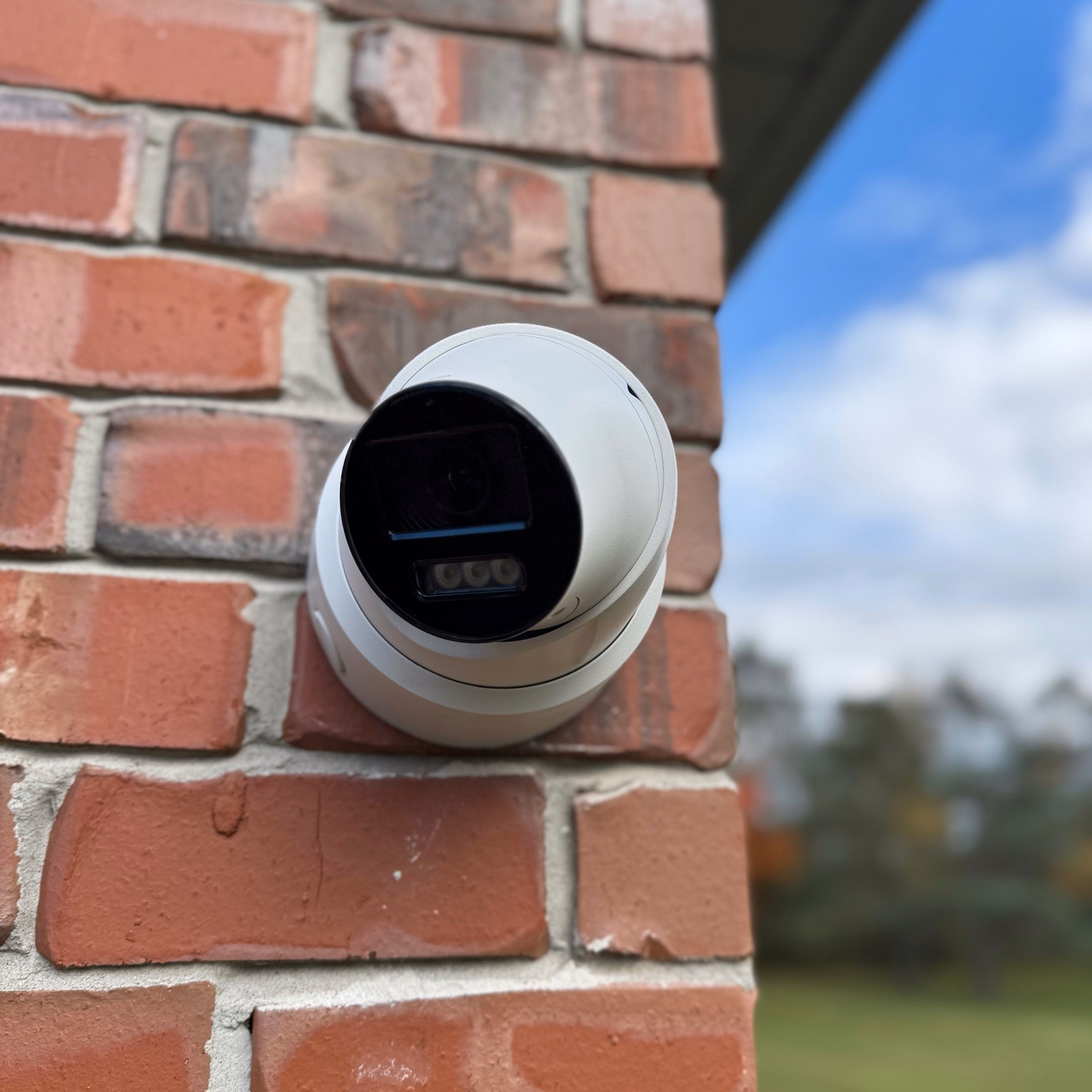 White security camera mounted on red brick beside a blue sky in Scarborough