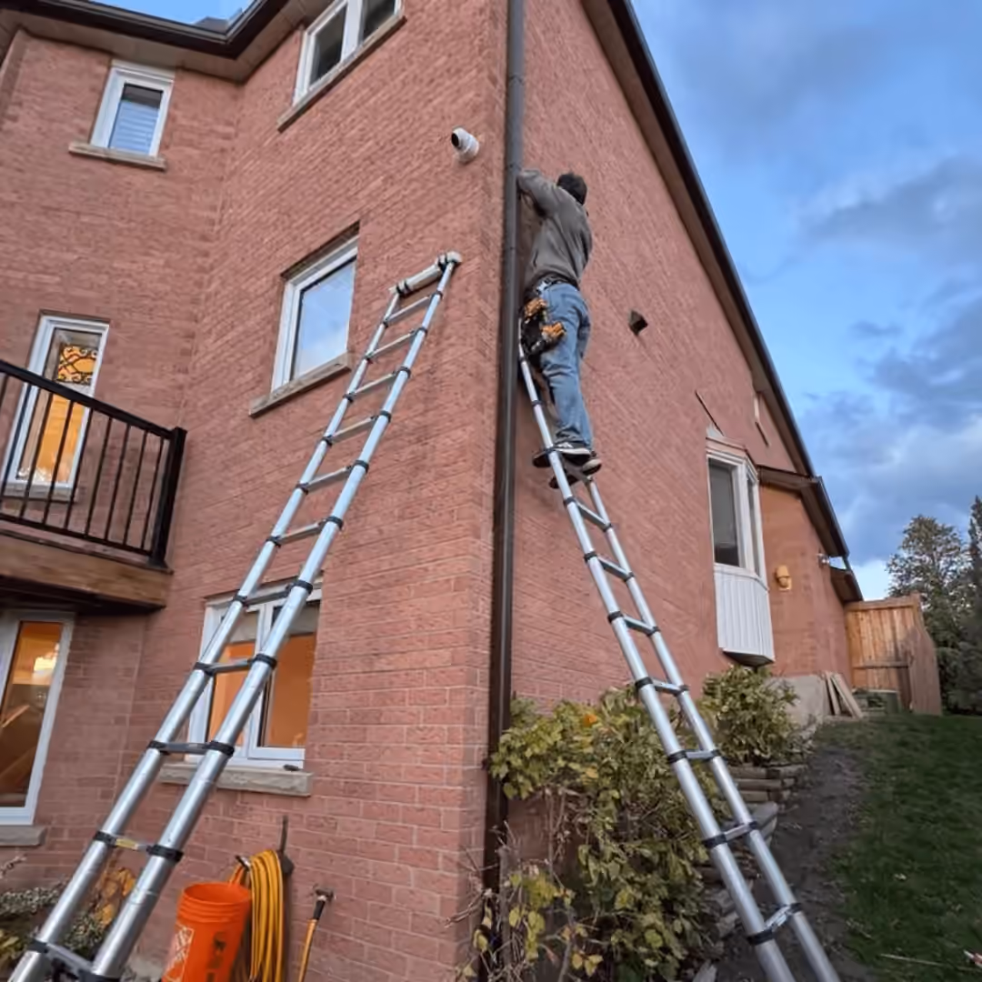 Technician installing a security camera beside a brick house